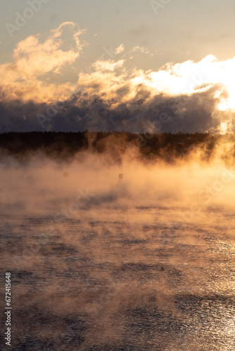 Sunrise over foggy ocean with bell.