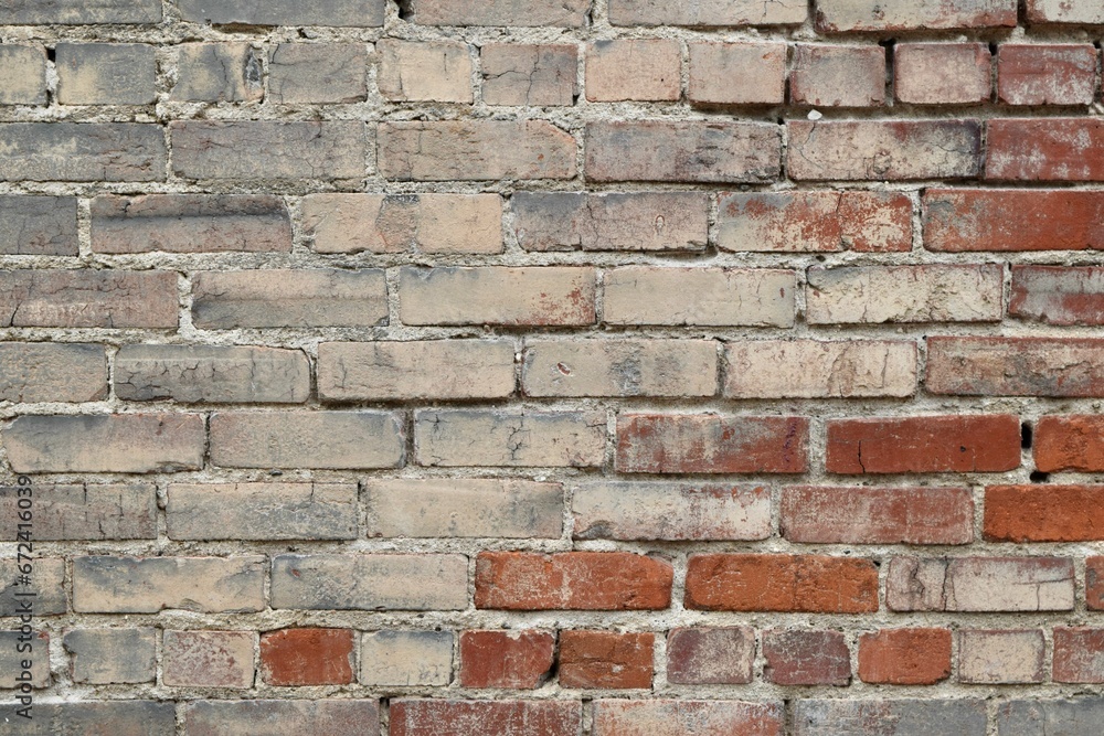 Weathered brick wall with a textured surface and cracks visible on the surface. Weathered brick wall with a textured surface and cracks visible on the surface.