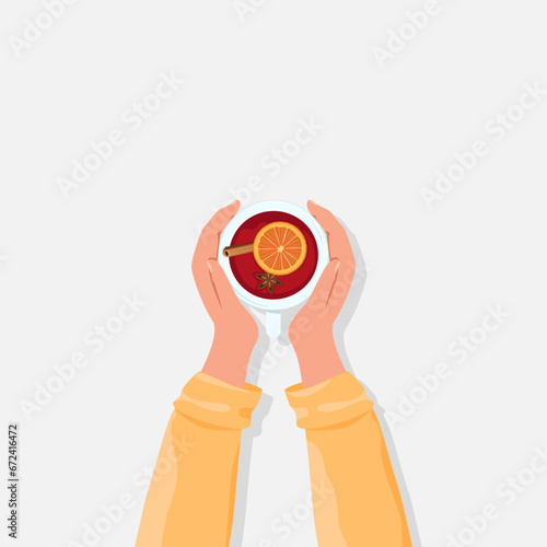 Hands hold a cup of fragrant hot mulled wine with various spices. Top view.