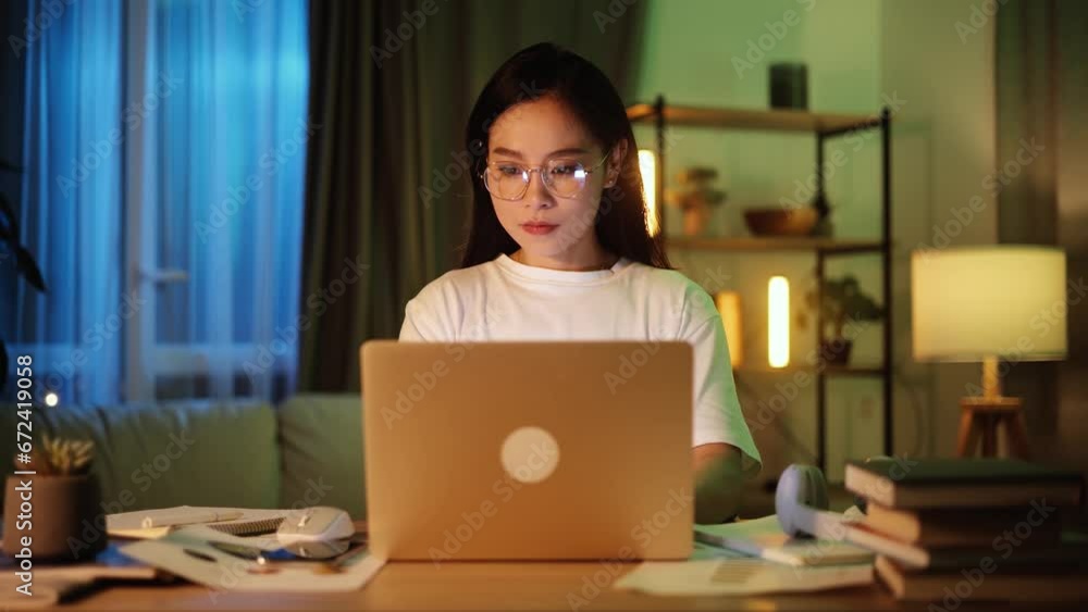 Confident freelancer with glasses having distance remote work typing browsing scrolling products in internet online store on laptop computer while sitting at desk workplace at late night at home Confident freelancer with glasses having distance remote work typing browsing scrolling products in internet online store on laptop computer while sitting at desk workplace at late night at home