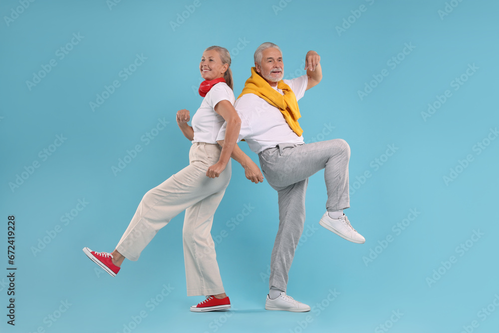 Senior couple dancing together on light blue background