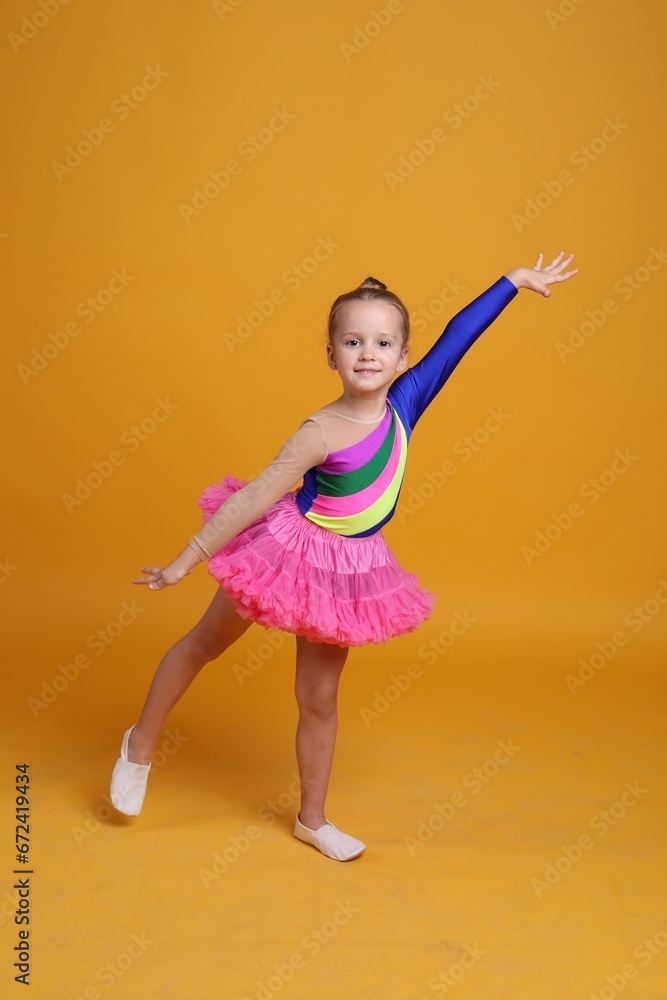 Cute little girl in costume dancing on orange background Cute little girl in costume dancing on orange background