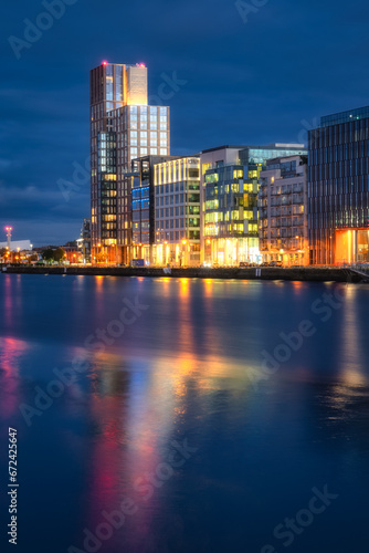 Modern offices and apartment buildings on Sir John Rogerson Quay  docklands  reflected in blurred Liffey River at dusk  blue hour  Dublin  Ireland