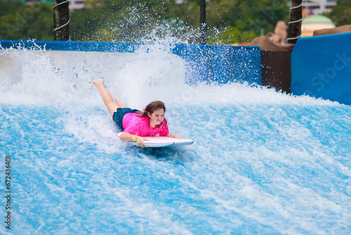 Canvas Print Child surfing in wave pool. Surfer training.