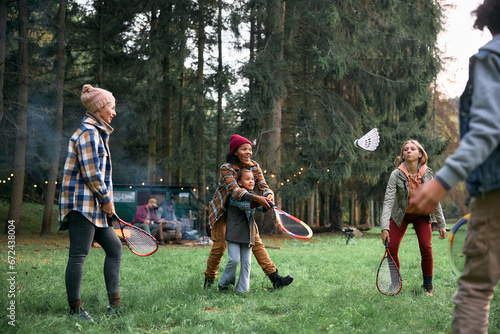 Happy family friends playing badminton while camping in nature.