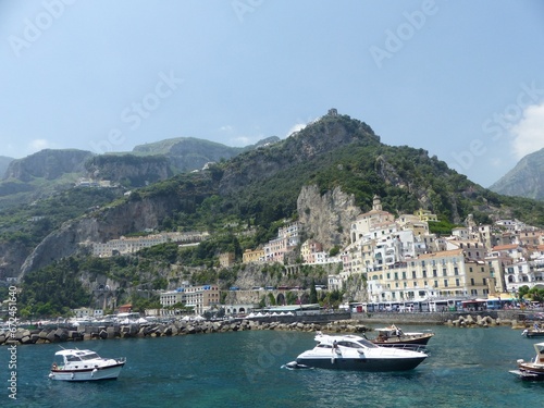 Coast of Amalfi with multiple boats against the background of mountains and town. Italy.