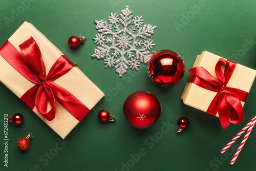 Christmas or New Year background. Craft paper gift boxes, with red ribbon, tie bow and Christmas balls on green background top view © kucherav