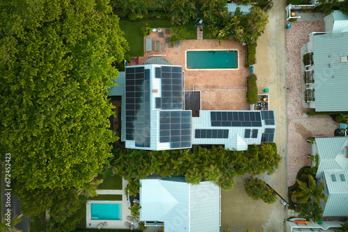 Aerial view of expensive american home with swimming pool and roof with blue solar photovoltaic panels for producing clean ecological electric energy. Renewable electricity with zero emission concept © bilanol