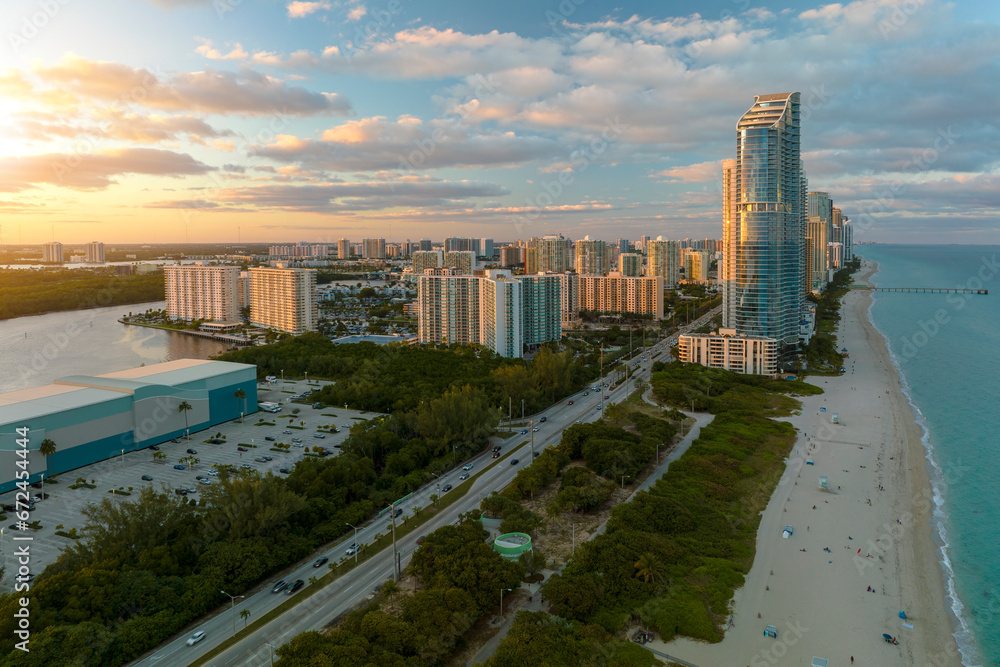 Evening landscape of sandy beachfront in Sunny Isles Beach city with luxurious highrise hotels and condo buildings on Atlantic ocean shore. American tourism infrastructure in southern Florida