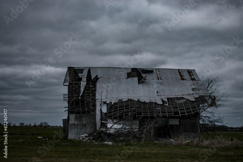 Old, dilapidated abandoned amid farmhouse in a forlorn farm, against the cloudy sky