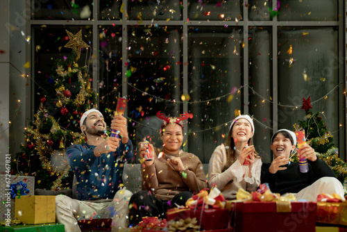 men and women using paper shoot in a party at living room. young couple Asian people enjoy celebrating Christmas and New Year. happy and celebrate with gift and presents.