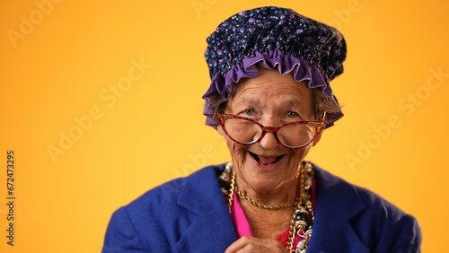 Closeup of funny happy smiling crazy grandmother mature woman, 80s, 90s, isolated on yellow background in studio © Robert Peak