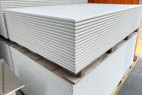 The stack of WHITE drywall Standard Gypsum board panel. Plasterboard. Panel Type A designed for indoor walls, partitions and ceilings, construction site photo