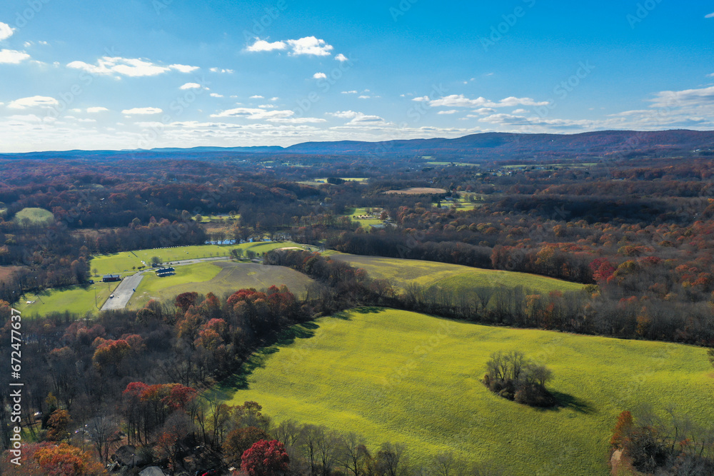 Wantage NJ farmlands with Kittatiny Mountain ridge and High Point monument in distant on sunny autumn day with fall foliage aerial