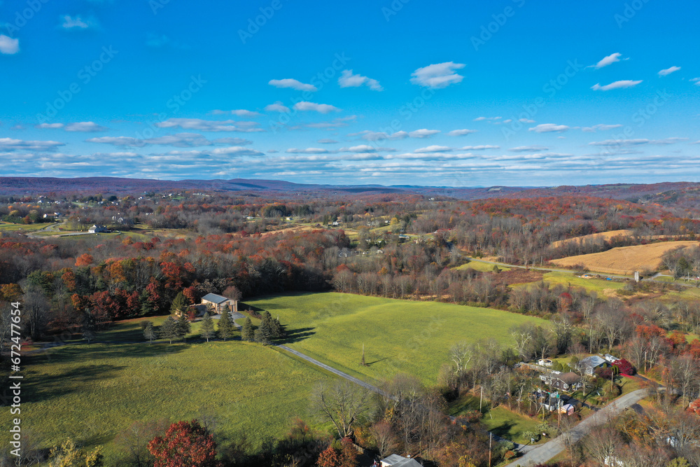 Wantage NJ farmlands with Kittatiny Mountain ridge and High Point monument in distant on sunny autumn day with fall foliage aerial