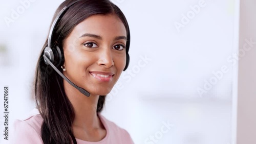 Call centre agent wearing headset and assisting with online enquiry for customer support service. Portrait of young sales representative smiling while making a sale at her helpdesk in the office