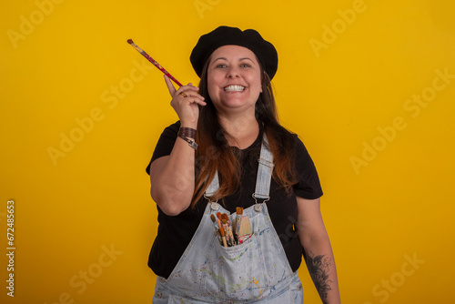Plus size woman in stylish clothes in studio photos, with facial expressions and with paintbrushes in hand