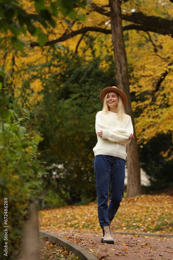 Happy woman wearing warm sweater walking in autumn park Happy woman wearing warm sweater walking in autumn park