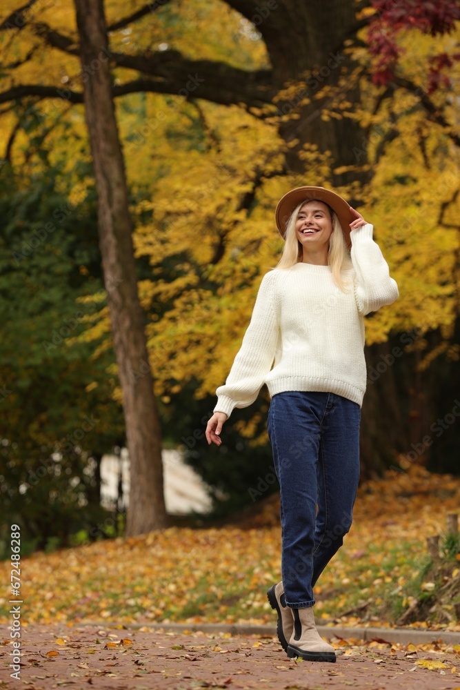 Happy woman wearing warm sweater walking in autumn park Happy woman wearing warm sweater walking in autumn park