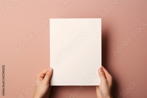 両手で白いA4用紙を持っているモックアップ
背景ピンクベージュ photo