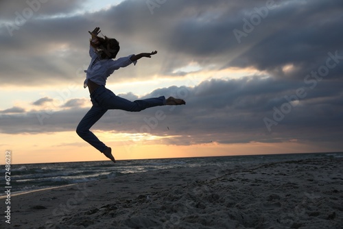 Beautiful woman dancing on beach at sunset