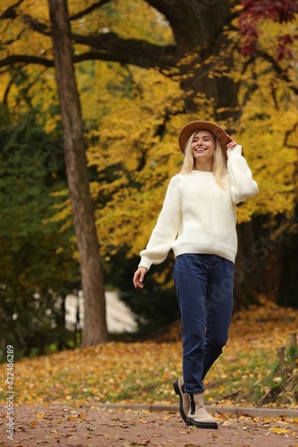 Happy woman wearing warm sweater walking in autumn park
