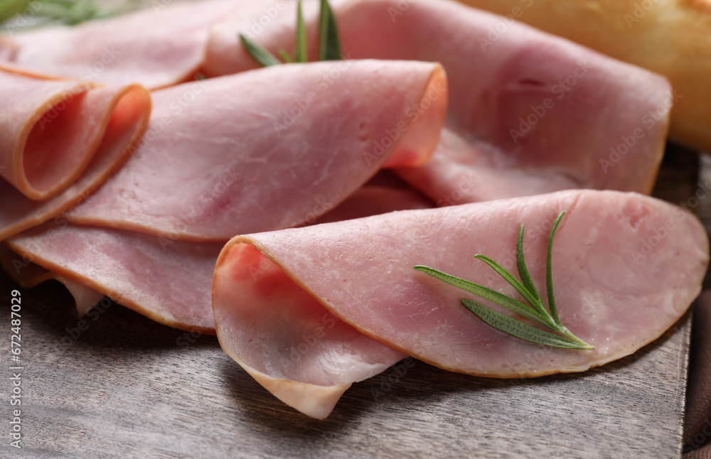 Slices of delicious ham and rosemary on wooden board, closeup Slices of delicious ham and rosemary on wooden board, closeup