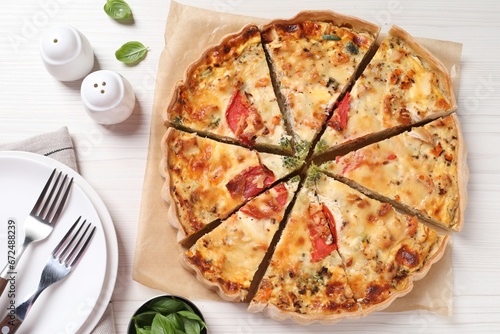 Tasty quiche with tomatoes and cheese served on white wooden table, flat lay
