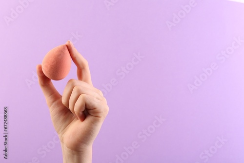 Woman with makeup sponge on violet background, closeup. Space for text