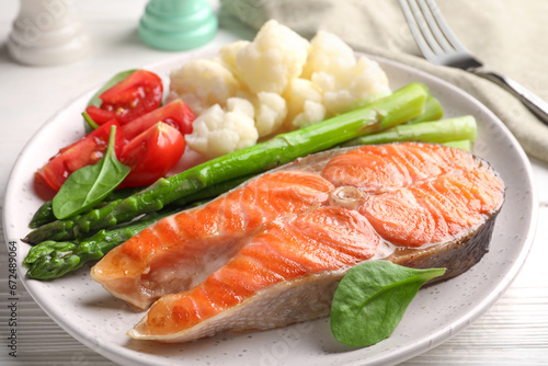 Healthy meal. Grilled salmon steak and vegetables served on white wooden table, closeup