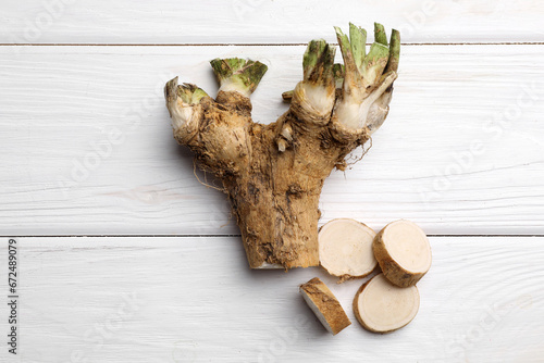 Cut horseradish root on white wooden table, flat lay