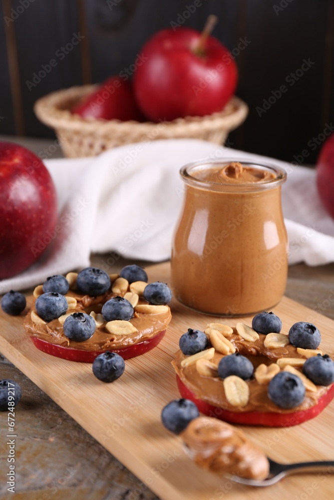 Slices of fresh apple with peanut butter and blueberries on wooden table, closeup