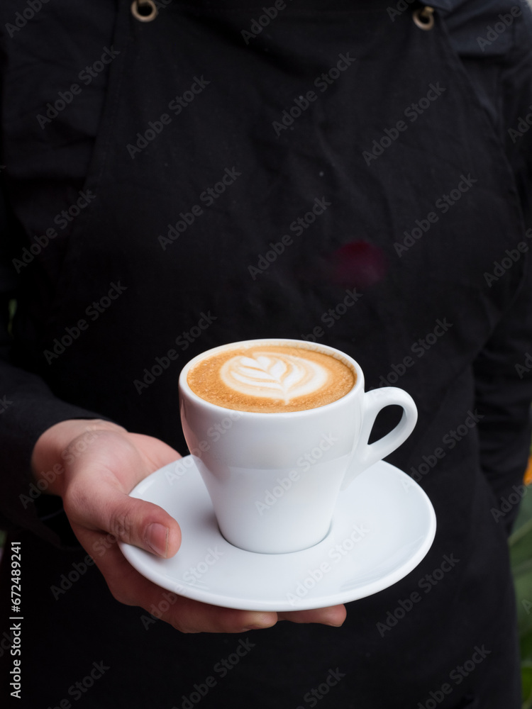Hand holding a cup of cappuccino. Hand holding a cup of cappuccino.