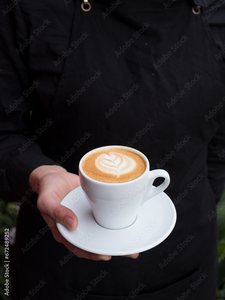 Hand holding a cup of cappuccino. Hand holding a cup of cappuccino.