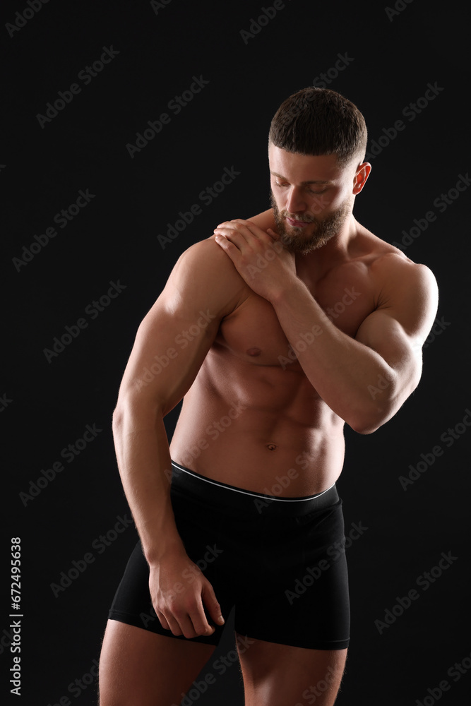 Young man in stylish underwear on black background