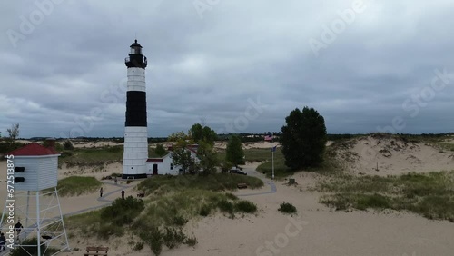 Big Sable Lighthouse on Lake Michigan. Aerial flyover of the site, showing the fog horn, lighthouse and keepers house, from offshore to onshore. Lower shot, approximately midheight of the lighthouse.