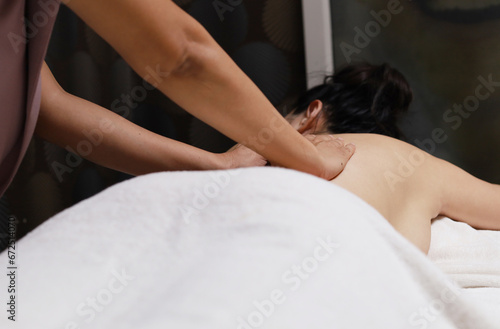 Close up beautiful giving a back massage to a young woman in a spa salon.
