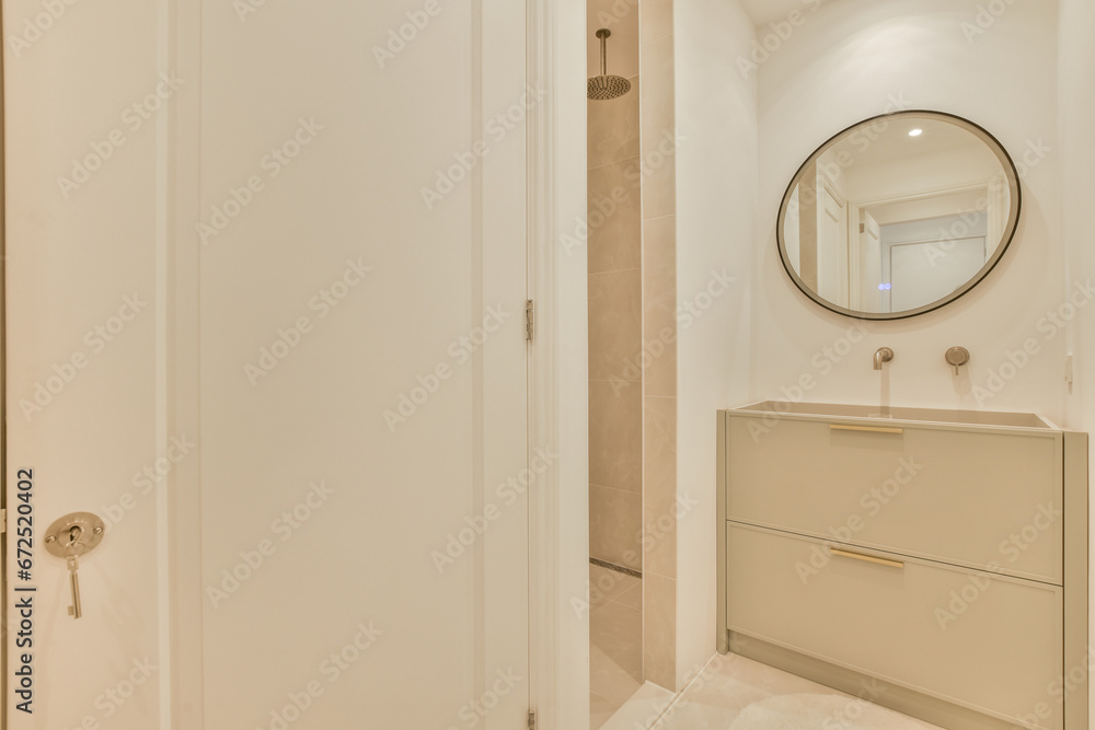 a bathroom with a mirror on the wall and white cupboards in front of the bathtub is next to the door a bathroom with a mirror on the wall and white cupboards in front of the bathtub is next to the door