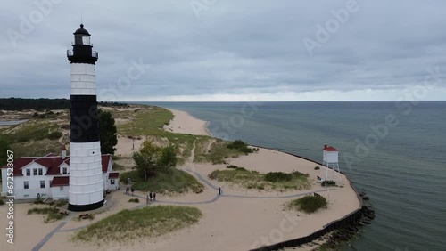 Big Sable Lighthouse on Lake Michigan. Aerial flyover shot, along the shore from north to south, featuring the lighthouse, keepers quarters, fog horn and related structures.