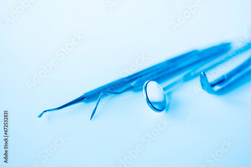 Dental mirror and other tools on blue shiny background.Dental tools on a blue background with reflection. Dentistry concept.Dental equipment placed on the table.