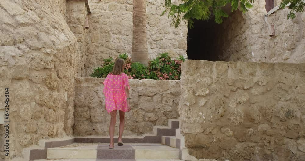 Teen girl in beach tunic coming up ladder to stone hotel on tropical resort. Blonde tourist teenager enjoying resting in beautiful place go to room, back view. Travel tourism vacation summer holidays. Teen girl in beach tunic coming up ladder to stone hotel on tropical resort. Blonde tourist teenager enjoying resting in beautiful place go to room, back view. Travel tourism vacation summer holidays.