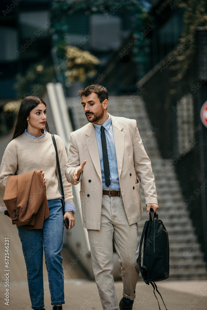 Naklejka premium Two colleagues strategizing while walking through the downtown area