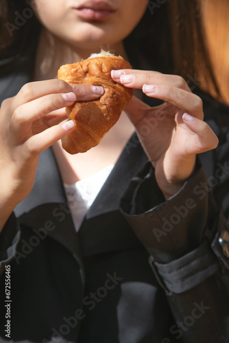 Young caucasian woman eating croissant.