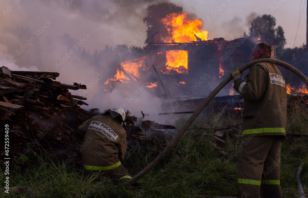 Fire service employees extinguish the fire. Firefighters at the scene of the fire. A fire in the village. Burning wooden houses in the village of Rantsevo, Tver region.