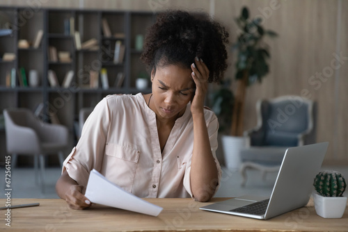 Shocked frustrated young African American woman getting document with bad news. Student girl receiving letter from college, rejection notice from university, reading paper, feeling sad, upset photo