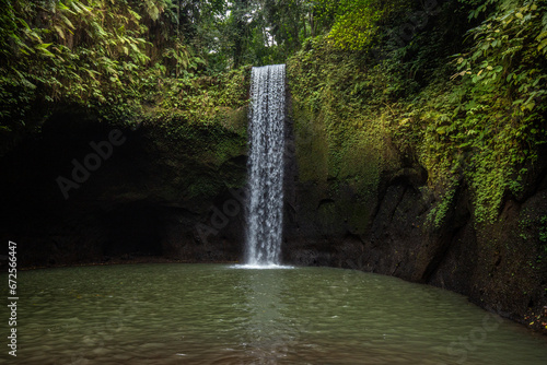 Tibumana Waterfall a small wide waterfall in a green gorge. The river falls into a basin in the middle of the forest. Excursion destination near Ubud, Bali photo