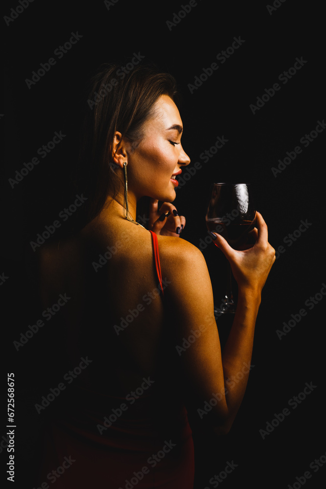 A glass of red wine in the hands of a sexy woman in a red dress A glass of red wine in the hands of a sexy woman in a red dress