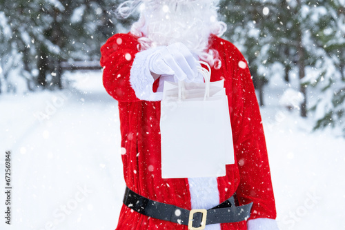 Santa Claus outdoor in winter and snow handing in hand paper bags with craft gift, food delivery. Shopping, packaging recycling, handmade, delivery for Christmas and New year