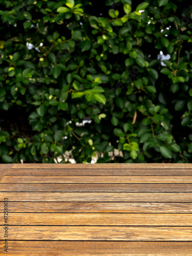 Mock up empty wood plank top table texture on blur fresh green garden background. Template of brown wooden desk, vertical. Blank space at vintage natural rustic wood background, for product advertise.
