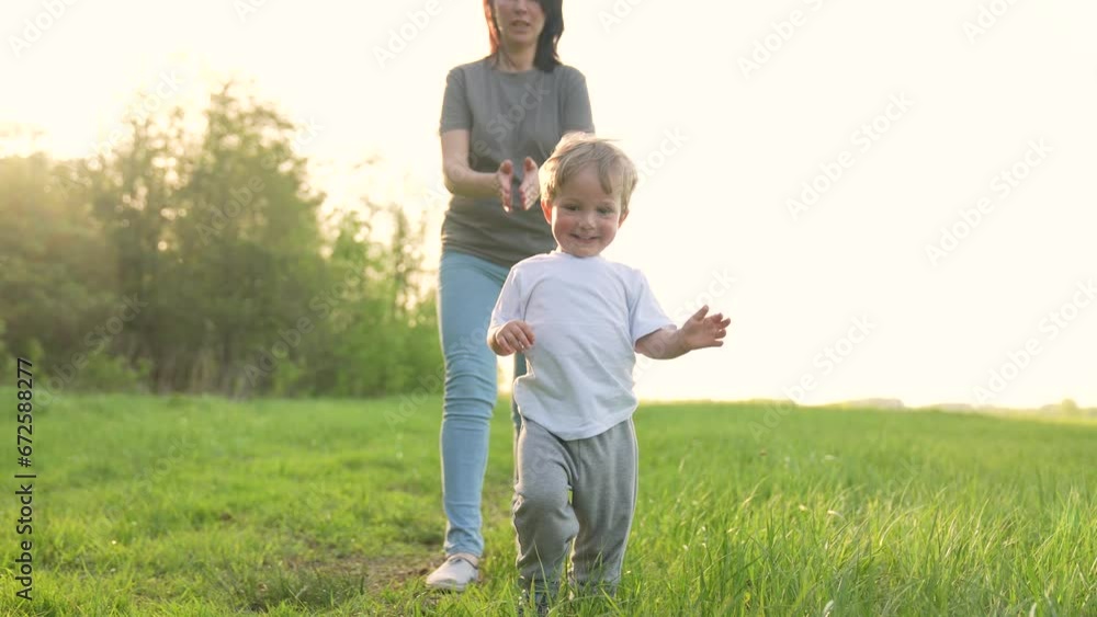 Happy family concept. happy guy. walk on green grass in the park. healthy outdoor lifestyle. active summer holiday. a child's dream. mother and baby run in nature on green grass. playing tag outdoors Happy family concept. happy guy. walk on green grass in the park. healthy outdoor lifestyle. active summer holiday. a child's dream. mother and baby run in nature on green grass. playing tag outdoors